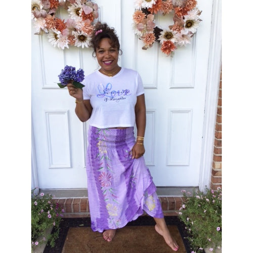 Model wearing top with it paired with lavender and lilacs dress/skirt.